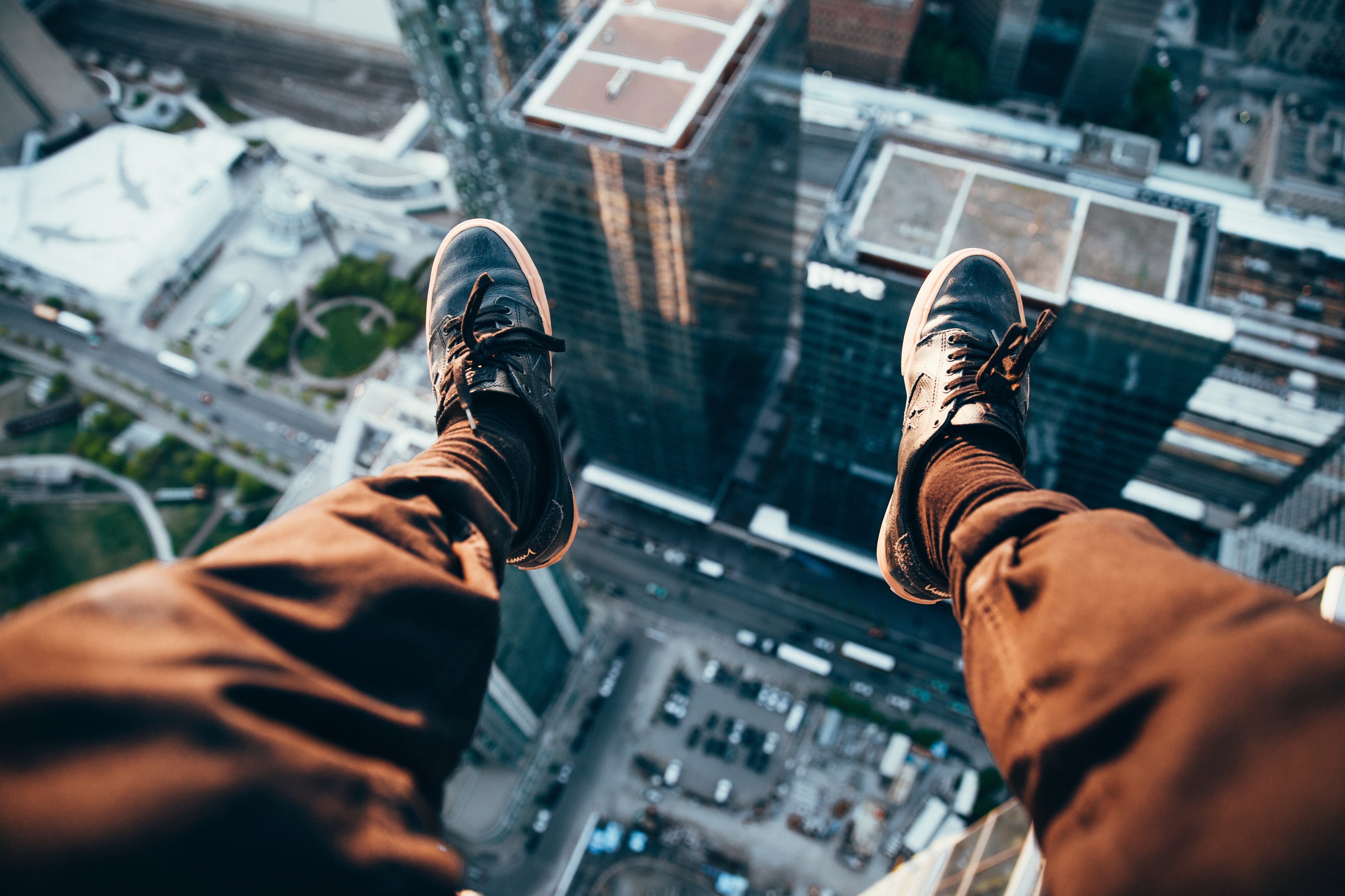 A bold perspective of a person dangling their legs over a city skyline, capturing the thrill of fearless style and urban adventure.